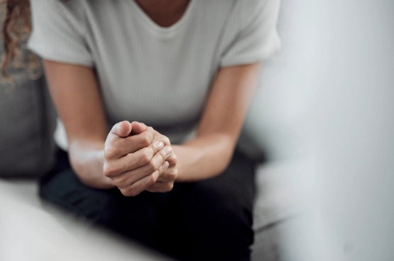 Research 16 Person sitting with hands clasped in thoughtful pose